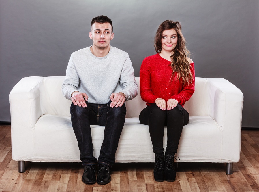 Shy woman and man sitting on sofa. First date.